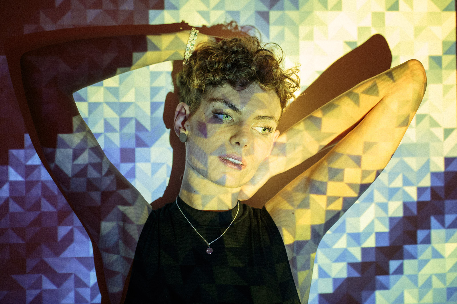 portrait of young woman with short curly hair with projected image of art