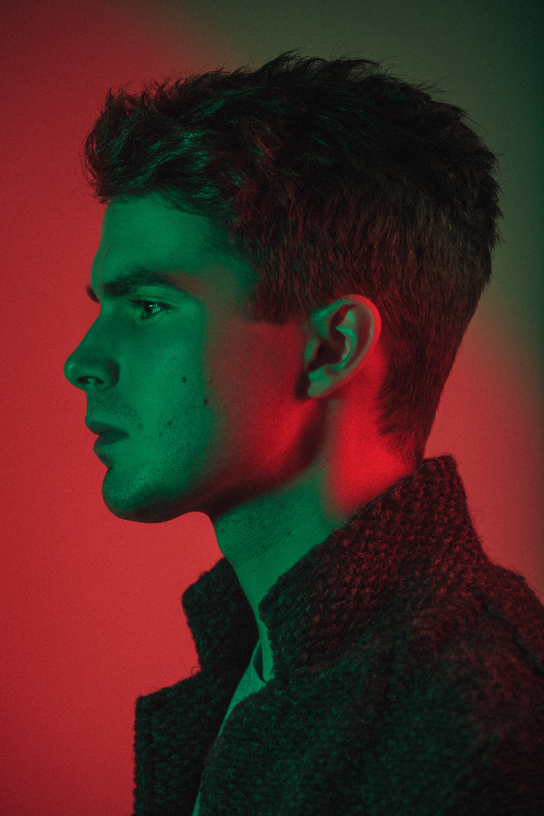 side profile portrait of young man with green and red studio light